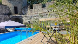 a swimming pool with a table and an umbrella at À L'AISE - Chambres d'hôtes à Vianne in Vianne
