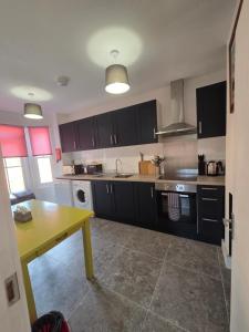 a kitchen with black cabinets and a yellow table at St Marys Cottages 1 in Dover