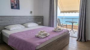 a bedroom with two towels on a bed with a balcony at Blue Sea Apartments in Qeparo
