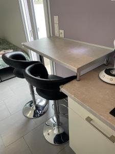 a counter with two black chairs next to a table at Studio de plein pied avec terrasse in Joncherey