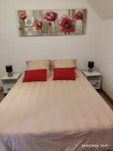 a bedroom with a white bed with two red pillows at Gîte pres de Giverny in Gasny