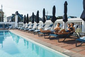 a group of people sitting on lounge chairs next to a pool at Oceana By The Sea in Point Pleasant Beach