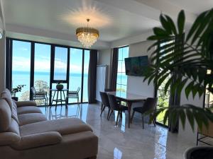 a living room with a couch and a table and chairs at Modern Villa - infinity pool & Panoramic Sea View in Kvariati