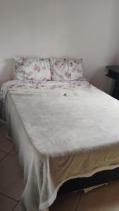 a bed with white sheets and red flowers on it at Recanto Vieira in Lages