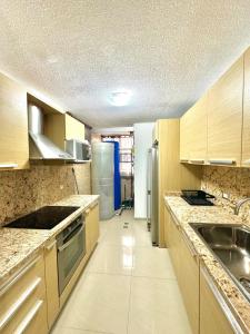 a kitchen with wooden cabinets and stainless steel appliances at Genoves Suite muy centrico in Porlamar