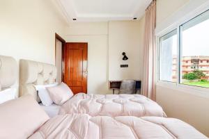 a bedroom with two beds and a window at Eden Appartement avec Piscine Et Salle de Sport in El Jadida +31 photos