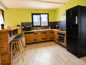 a kitchen with a black refrigerator and wooden cabinets at Villa des trois singes in Saint-Pierre +10 photos