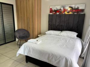 a bedroom with a white bed and a chair at Cozy&Pristine The Blyde in Pretoria +21 photos