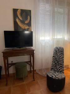 a living room with a television and a desk with a chair at Mex-Goretti House in Mairena del Aljarafe