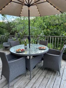 a table with chairs and an umbrella on a deck at Tiggywinkle Beck Lodge in Windermere