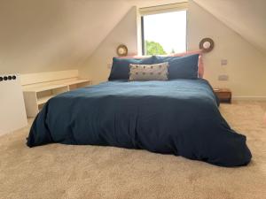 a bed with a blue comforter in a bedroom at Little Rozel in East Grinstead