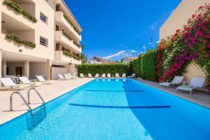 a swimming pool in a hotel with chairs and flowers at BRESSOL DELUXE Apartments in Port de Pollensa