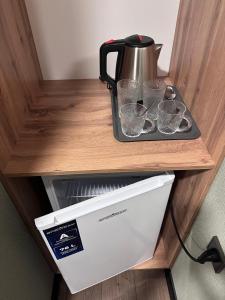 a tea kettle and four cups on a counter at GuestHouse-Medeu in Almaty