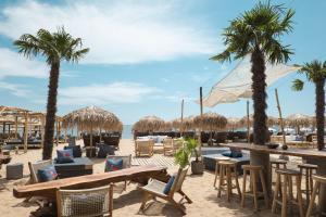 a beach with tables and chairs and palm trees at Seafront Apartment with Panoramic Terrace in Golden Sands