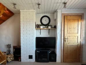 ein Zimmer mit einem Fernseher und einer Uhr an der Wand in der Unterkunft Seaside Cabin in Aabla