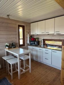 eine Küche mit weißen Schränken, einem Tisch und Stühlen in der Unterkunft Seaside Cabin in Aabla + 25 Fotos