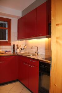 a kitchen with red cabinets and a sink at Chalet Bettlihorn in Ernen