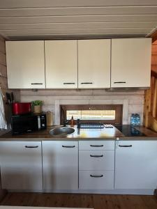 eine Küche mit weißen Schränken und einer Spüle in der Unterkunft Seaside Cabin in Aabla