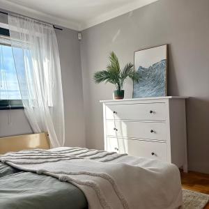 a bedroom with a bed and a dresser with a plant on it at Villa ZöldFüge in Balatonfůzfő