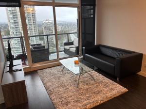 a living room with a black couch and a large window at Brentwood Retreat in Burnaby