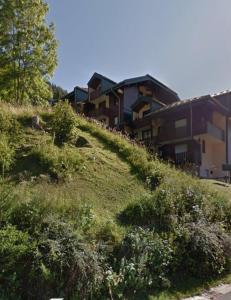 a building on the side of a grassy hill at Studio montagne in Mijoux