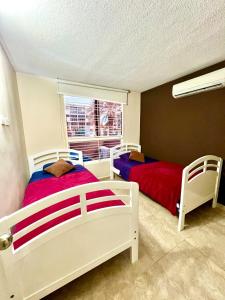 a bedroom with two beds and a window at Coral Suite Excellent location in Porlamar +9 photos