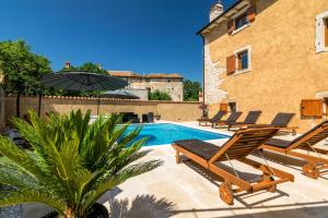 uma piscina com espreguiçadeiras ao lado de um edifício em Villa Sagri - heated pool em Žagrići