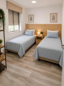 two beds in a room with wooden floors at Estafeta Apartament in Ponferrada