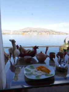 a table with food on it next to the water at Titicaca Lodge Flotante in Puno