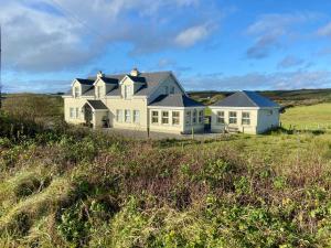 a large white house on a hill in a field at Fairy Fort View, Lahinch in Carrowauff