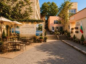 a patio with tables and chairs and a sign that reads white olympus at Hotel Olimpiya in Balchik