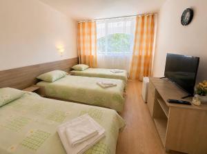 a room with three beds and a flat screen tv at Hotel Olimpiya in Balchik +11 photos