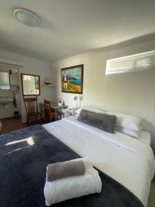 a bedroom with a large white bed and a table at Kelp Cottage - Two Private Garden en-suite Rooms in Gansbaai