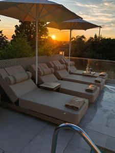 a group of couches and an umbrella next to a pool at Astre&Jeanne suites in Sozopoli