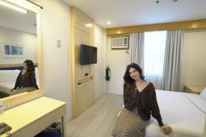 a woman standing in a hotel room with a mirror at Tom's Cabin Hotel in Cebu City