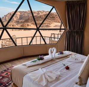 a bedroom with a swan decoration on a bed with a view at MAJDOLINE Desert Camp in Wadi Rum