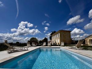 a swimming pool with chairs and a building at Maison Destieu in Saint-Sulpice-de-Faleyrens