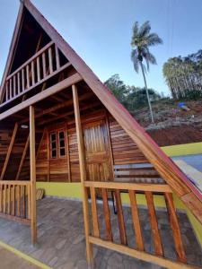 a large wooden building with a palm tree in the background at Pousada Vista da Mantiqueira - Chalés Sabiá, Beija-Flor e Siriema in Extrema