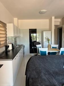 a kitchen with white cabinets and a table with blue chairs at La Terra Luxury apartment in Kiveri