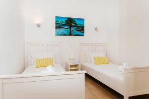 two white beds in a room with a picture on the wall at Maria's Village in Tavira +113 photos