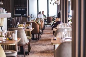 a restaurant with tables and chairs with people sitting at them at Hotel Kragujevac in Kragujevac
