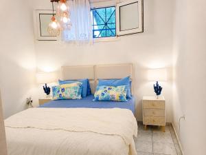 a bedroom with a bed with blue pillows and a window at Siviri Sea & Forest-Cozy Apartment with Garden & Nature Views in Siviri