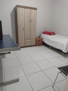a bedroom with a bed and a cabinet and a tiled floor at Pousada de Sá in Uberlândia