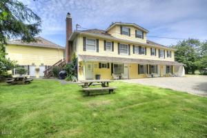 a yellow house with two picnic tables in the yard at Captain Cook Inn in Lincoln City