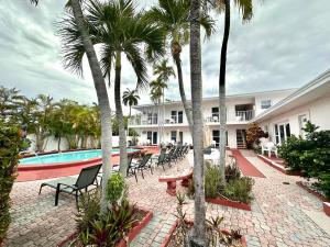 a resort with a pool and chairs and palm trees at Birch Patio Motel in Fort Lauderdale