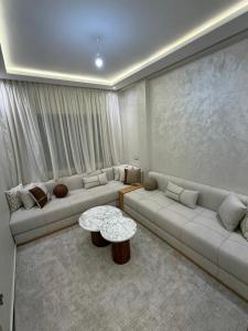 a living room with two couches and a table at Residence LINA in Bouznika