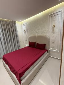 a white bedroom with a bed with red sheets at Residence LINA in Bouznika