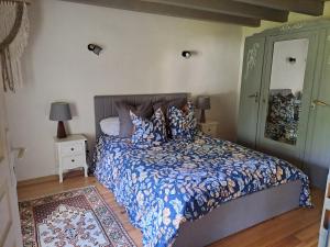 a bedroom with a bed with a blue comforter and a mirror at location gite chez DENIS in Alçay-Alçabéhéty-Sunharette
