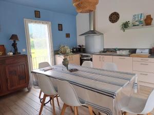 a kitchen with a table with white chairs and a kitchen with blue walls at location gite chez DENIS in Alçay-Alçabéhéty-Sunharette +4 photos