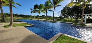 a swimming pool with palm trees in a park at Apartamento Frente al Mar en Río Hato, Playa Blan ca, Piscina y Acceso Directo a la Playa in Playa Blanca